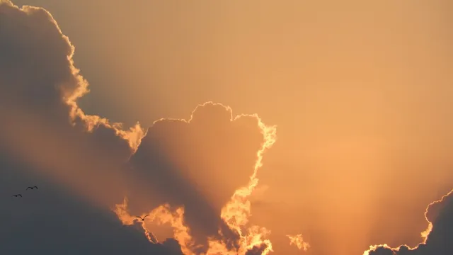 Sol saliendo entre nubes, con la luz cálida abriéndose paso