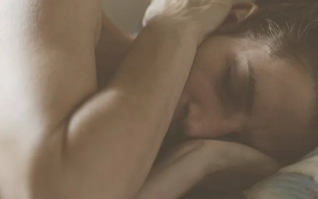 Mujer despierta en la cama, con el brazo doblado sobre la cabeza