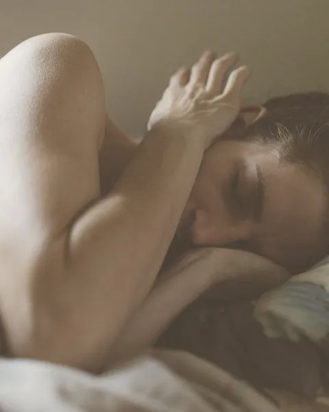 Mujer despierta en la cama, con el brazo doblado sobre la cabeza