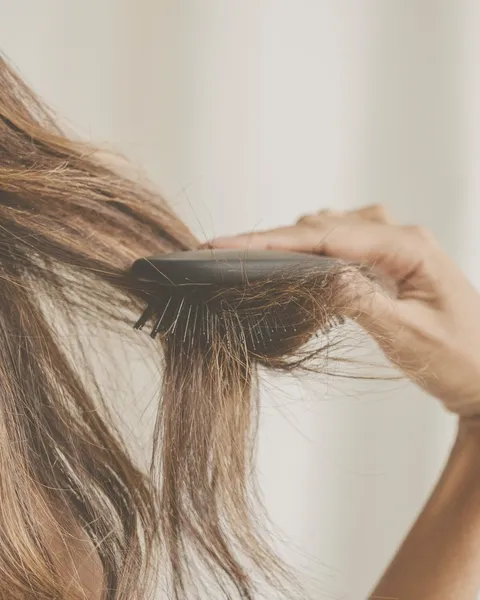 Cepillo con cabello enredado al pasarlo por una melena larga