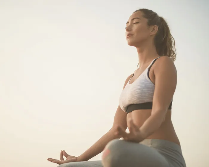 Mujer sentada a contraluz con los ojos cerrados, respirando despacio